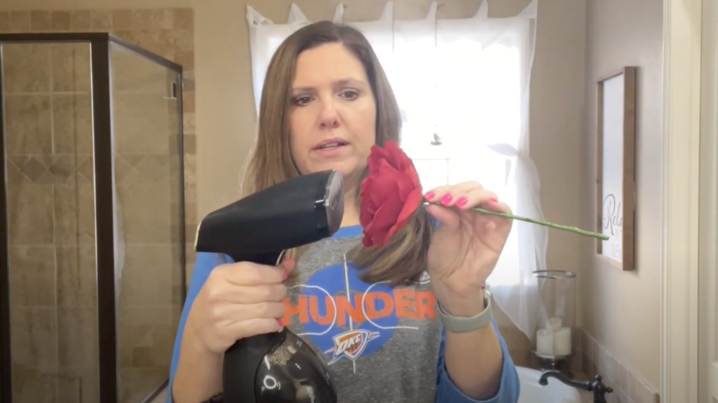 Lindsey holding a silk flower, blowing steam from her steamer into the petals of the silk flower