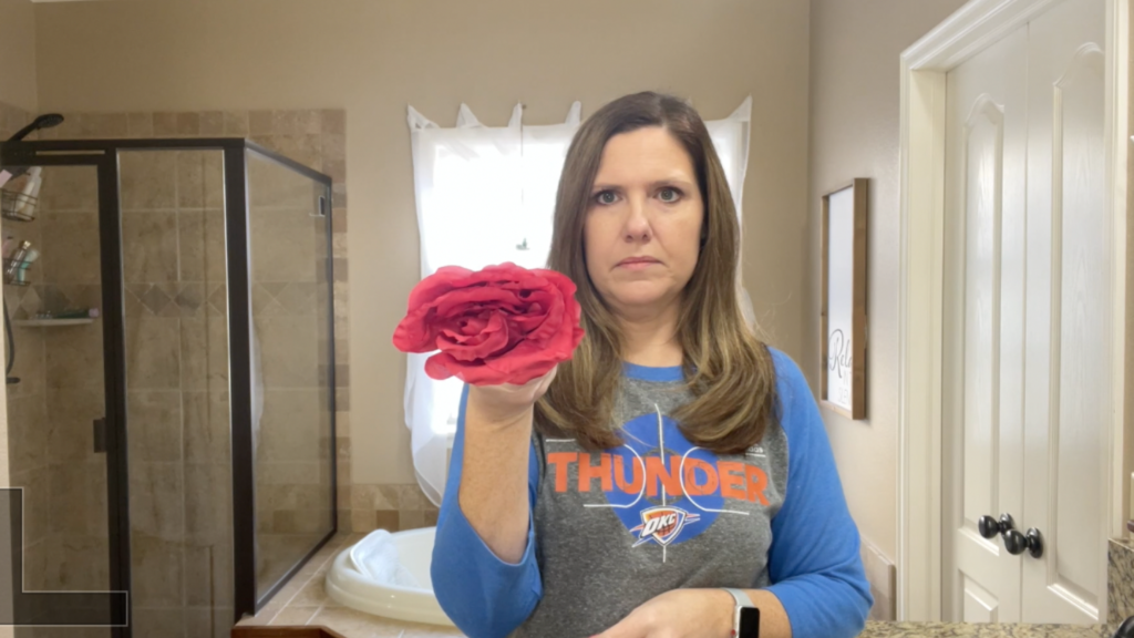 Lindsey holding a smushed silk flower, showing it to the camera