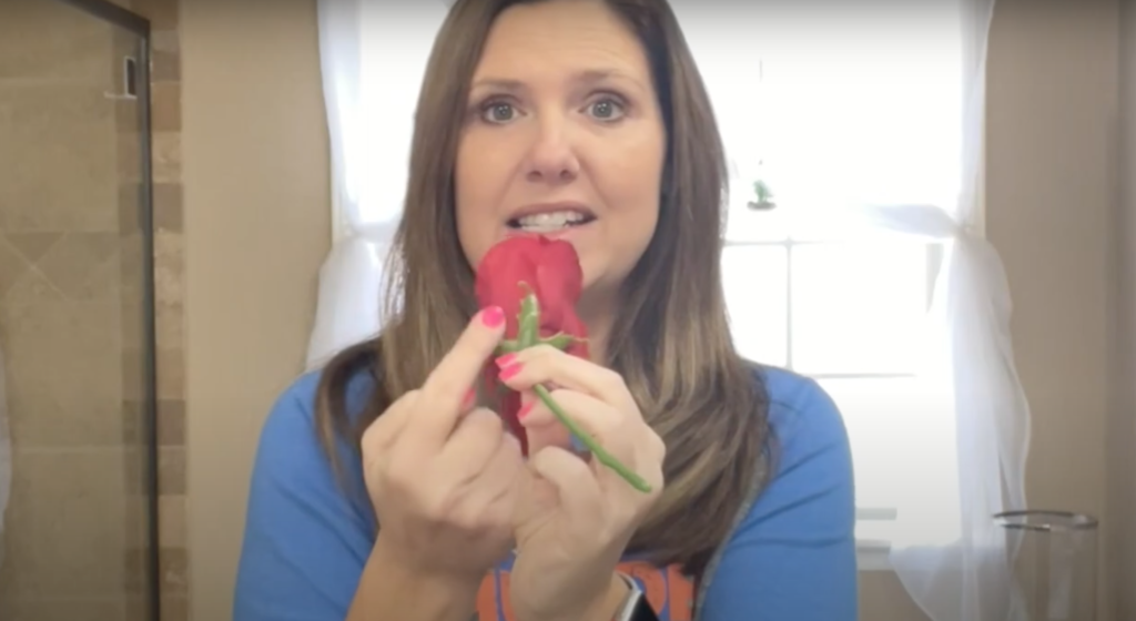 Lindsey holding a smushed silk flower, pointing to the stem