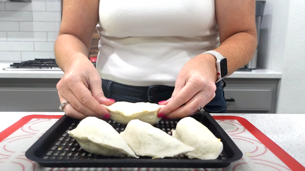 Lindsay placing the completed breakfast pockets on the air fryer tray to cook