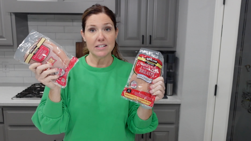 Lindsay holding up two chicken breast packages that she got from Costco.